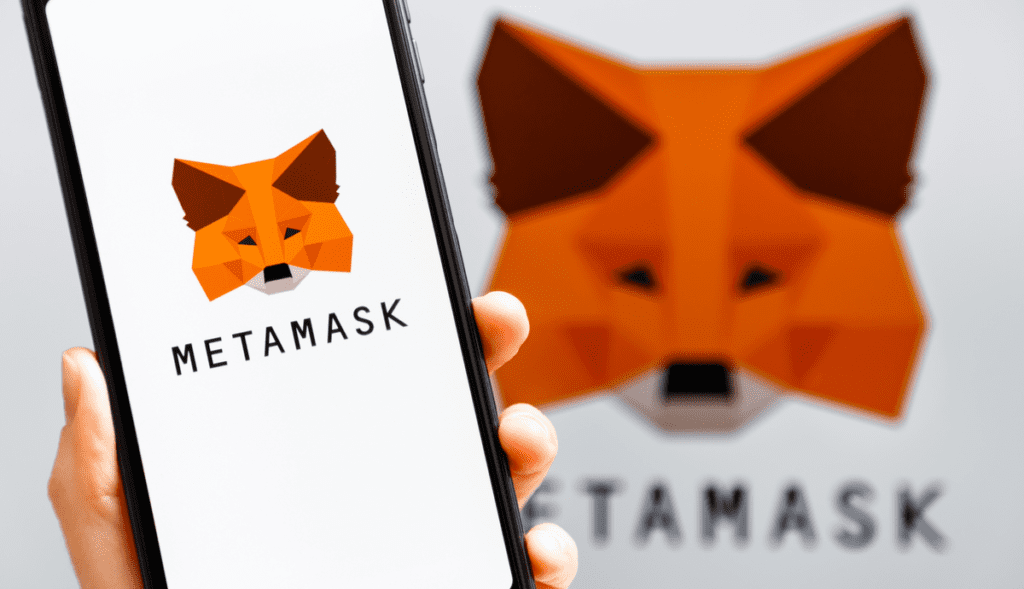 person holding a cellphone displaying Metamask logo