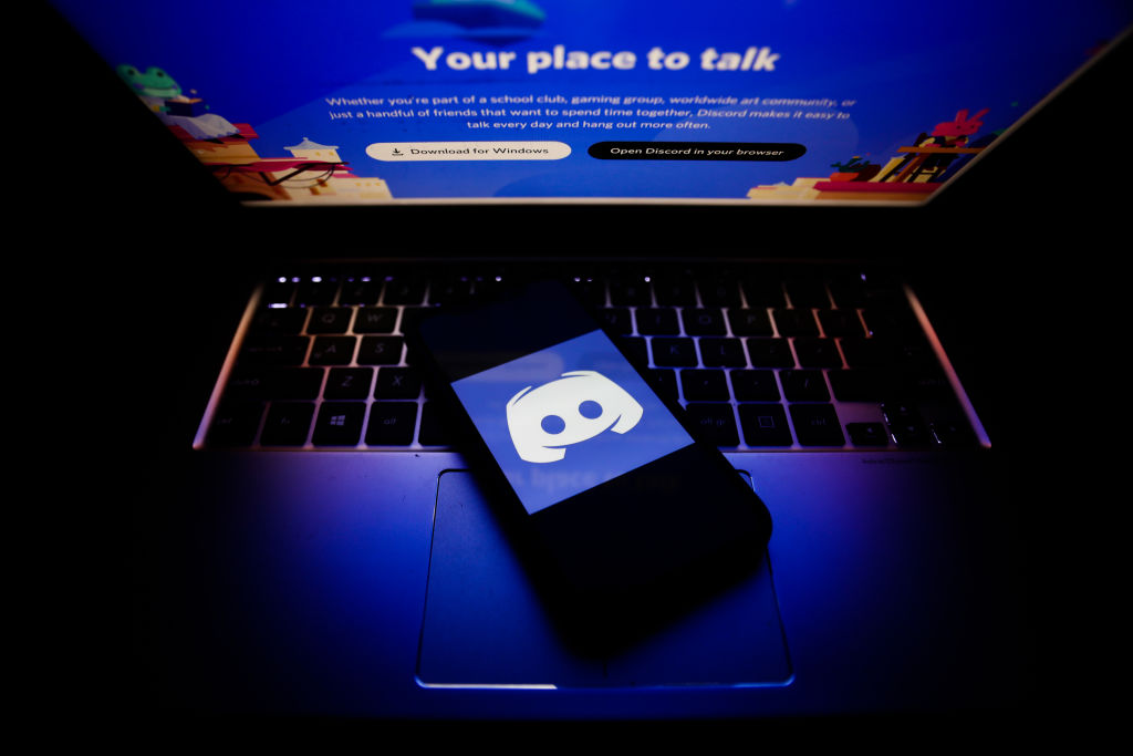 picture of a laptop displaying the home page from discord along with a smartphone displaying Discord's logo