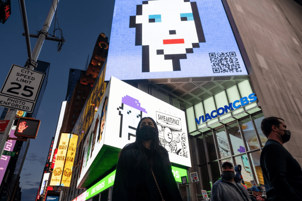 picture of times square showing multiple people walking on the streets and NFTs from the cryptopunks collection being displayed in the buildings